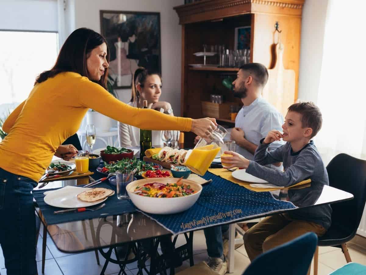 Family around table for dinner; mom pouring juice for son