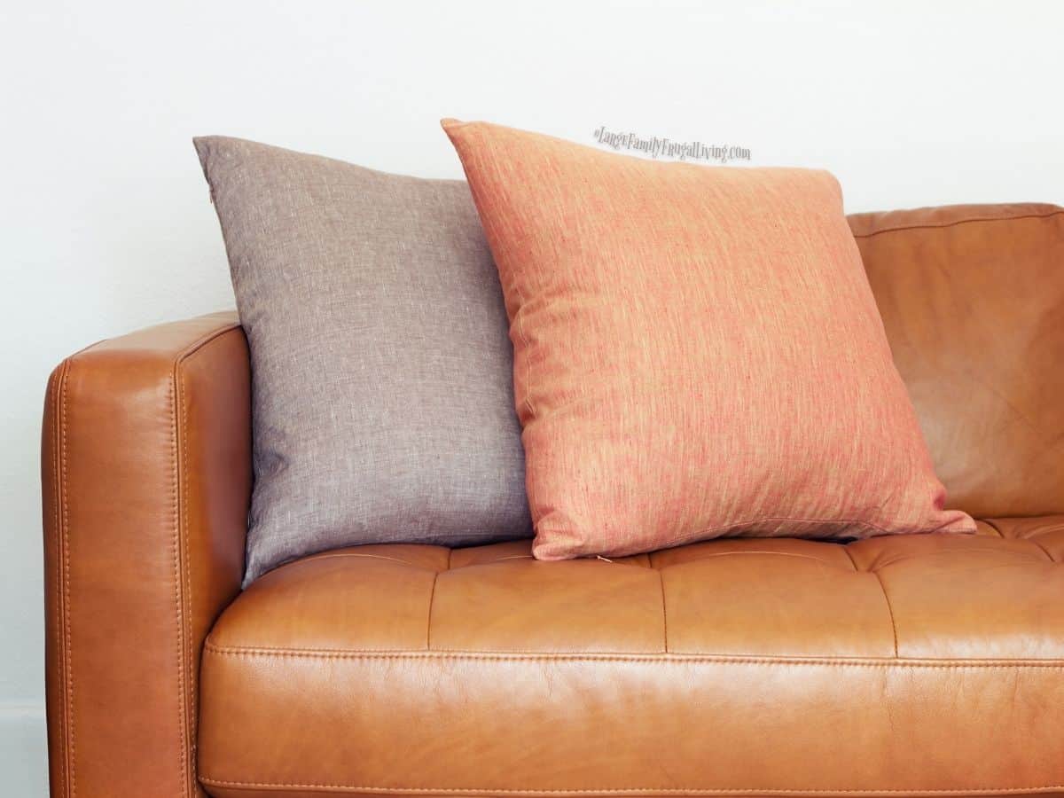 Close up of tan leather sofa with two linen pillows in different colors