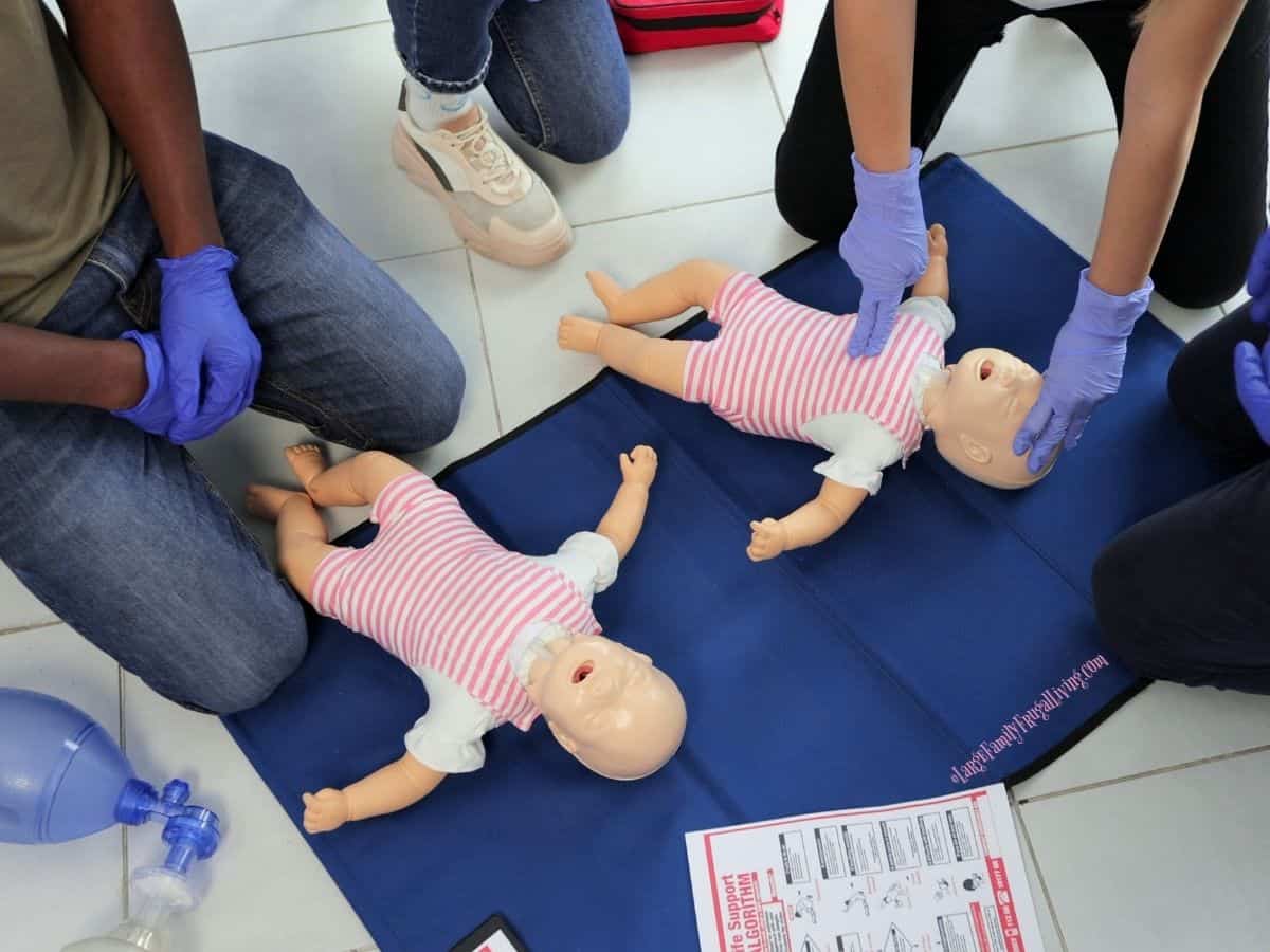 Group of four adults and two dummies learning infant CPR and first aid