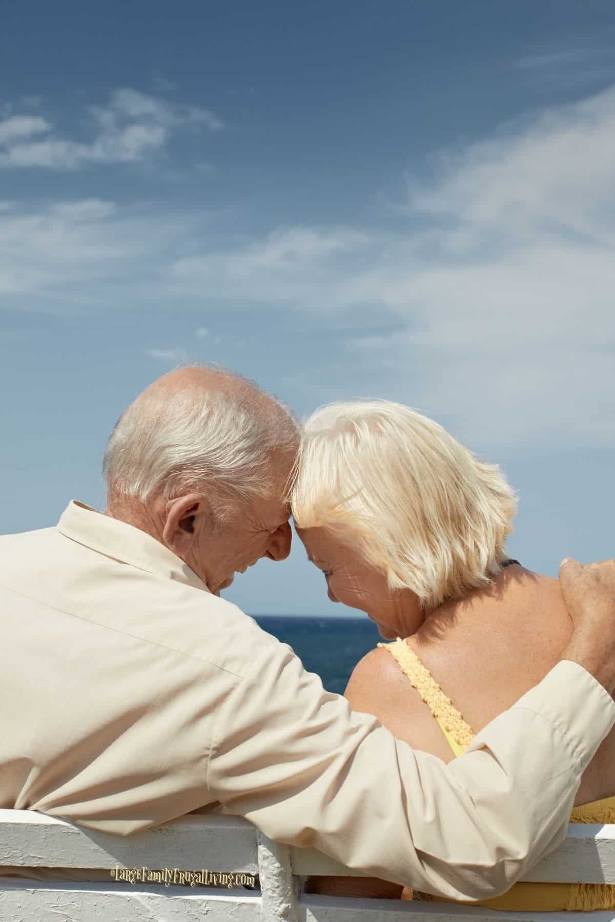 Senior couple sitting on bench near sea hugging