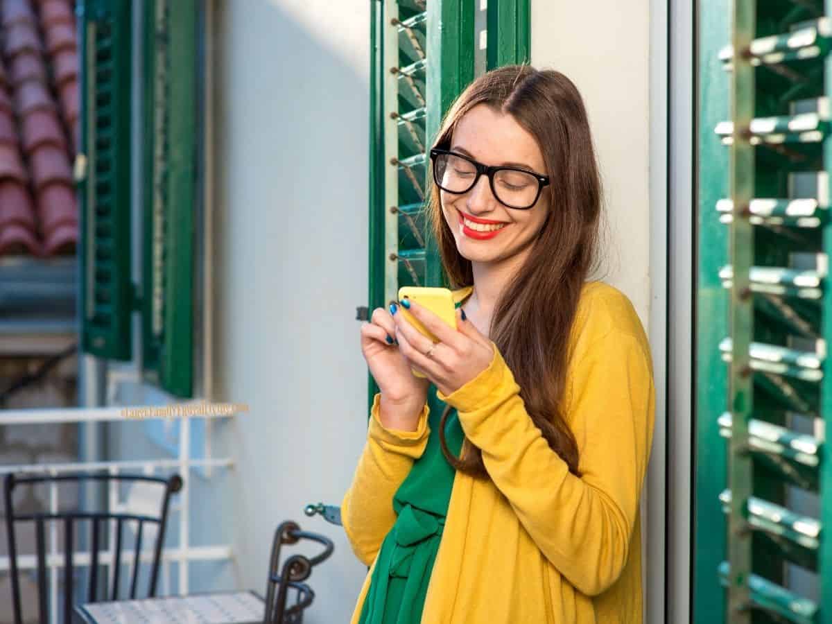 Woman in green dress and soft yellow cardigan standing on balcony