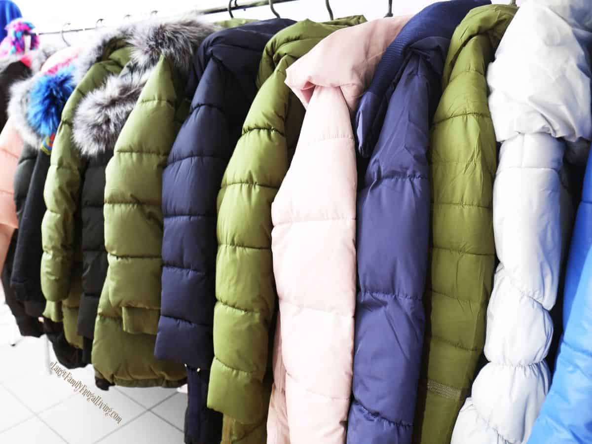 Winter coats in bright colors and range of sizes on a rack in a bright store