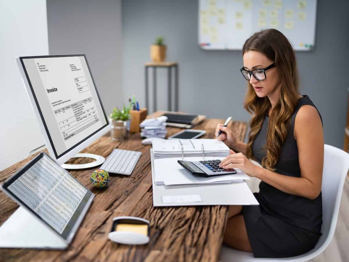Business woman at desk calculating invoice