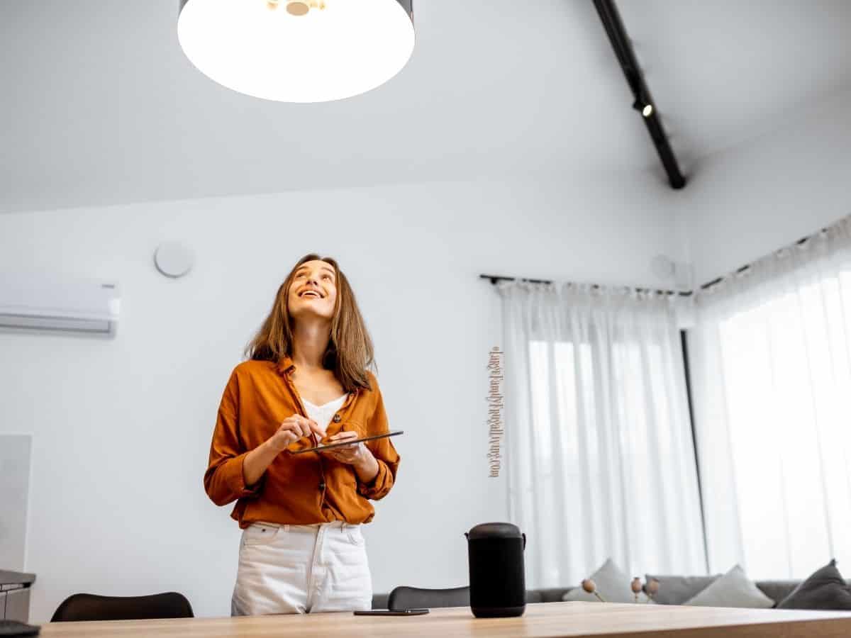 Young woman controlling smart light from tablet in a home