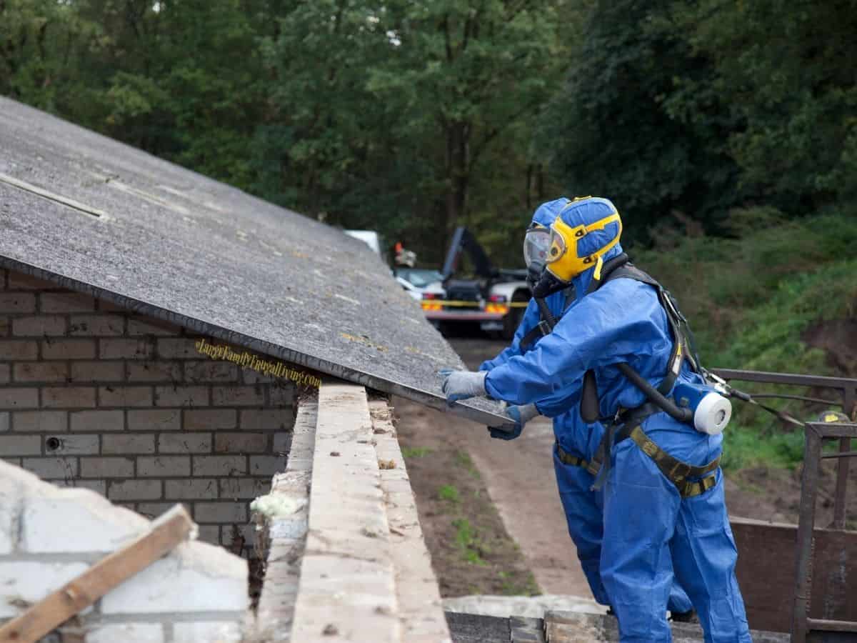 Asbestos removal and cleanup with workers in safety gear working on roof of a home.