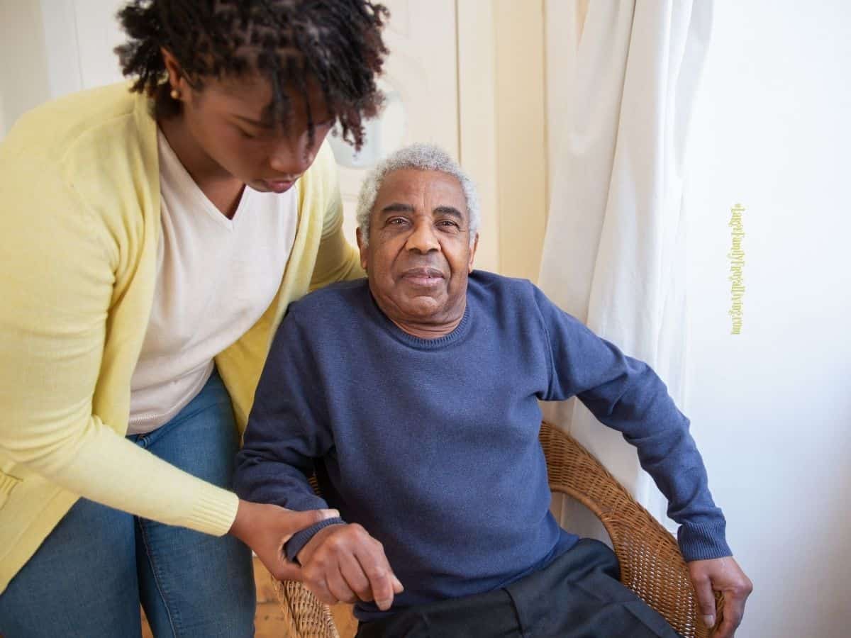 Younger woman assisting elderly family member in their home