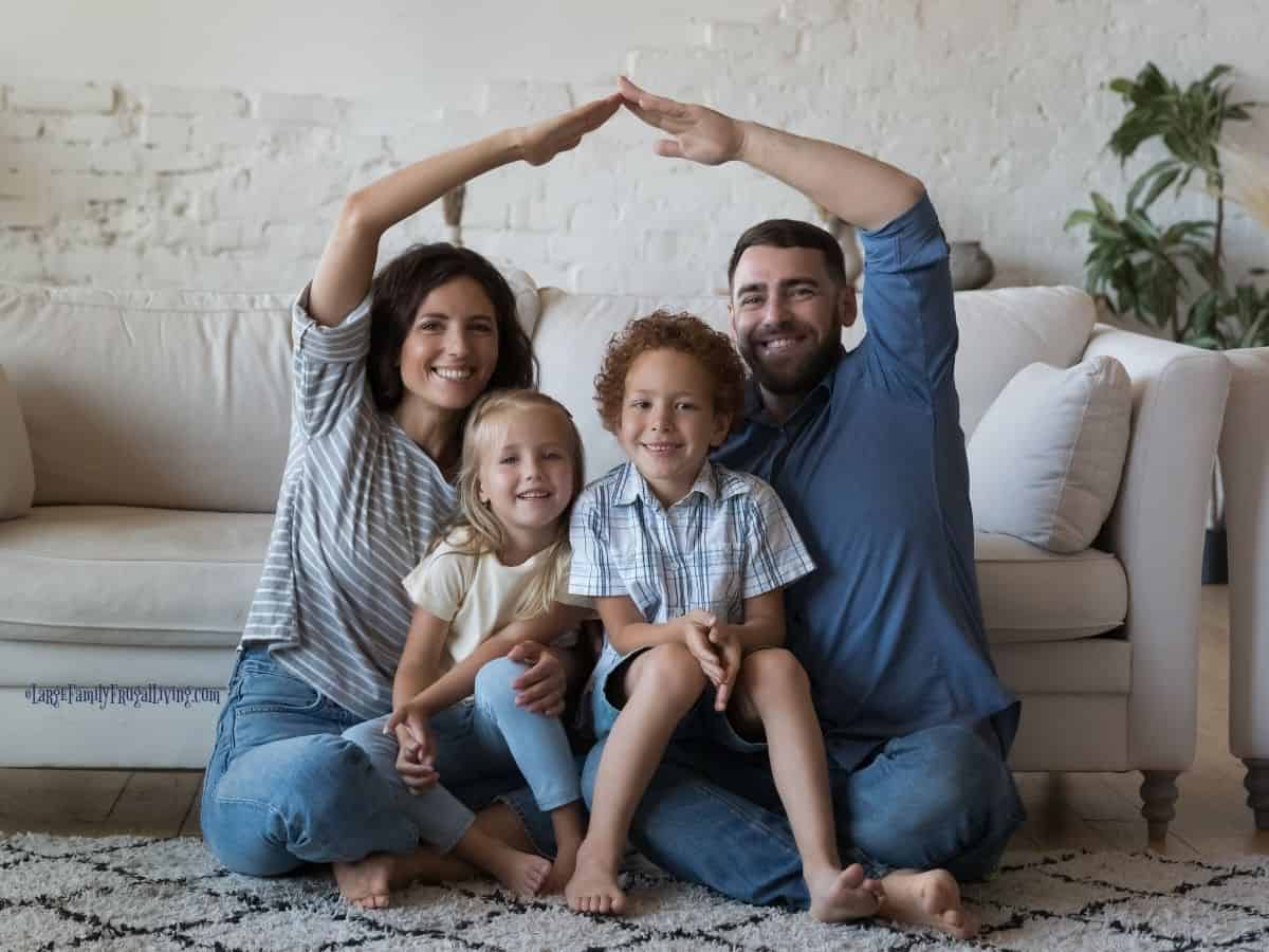Cute kids and loving parents sit on floor in warm living room; happy well-being and home
