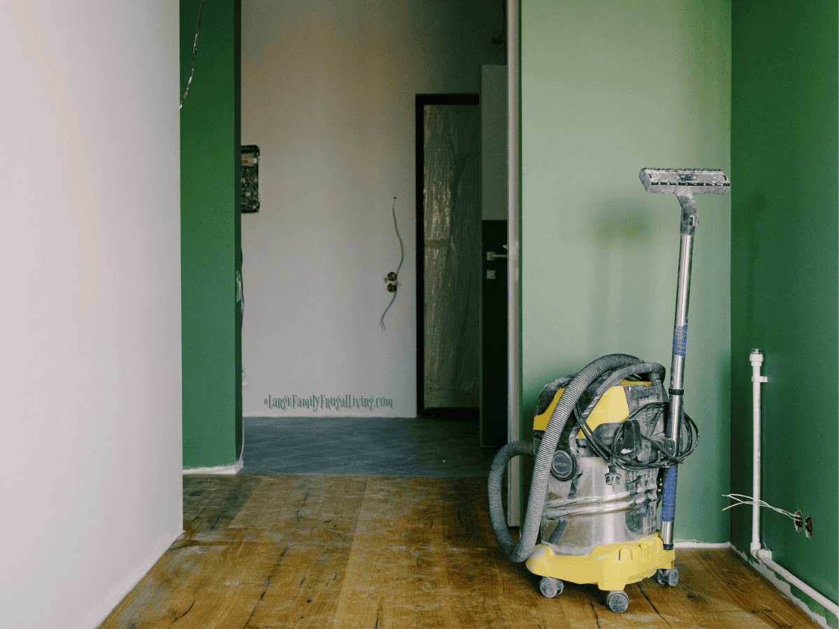 Green painted walls, wiring undone, construction dust, and vacuum cleaner in corner
