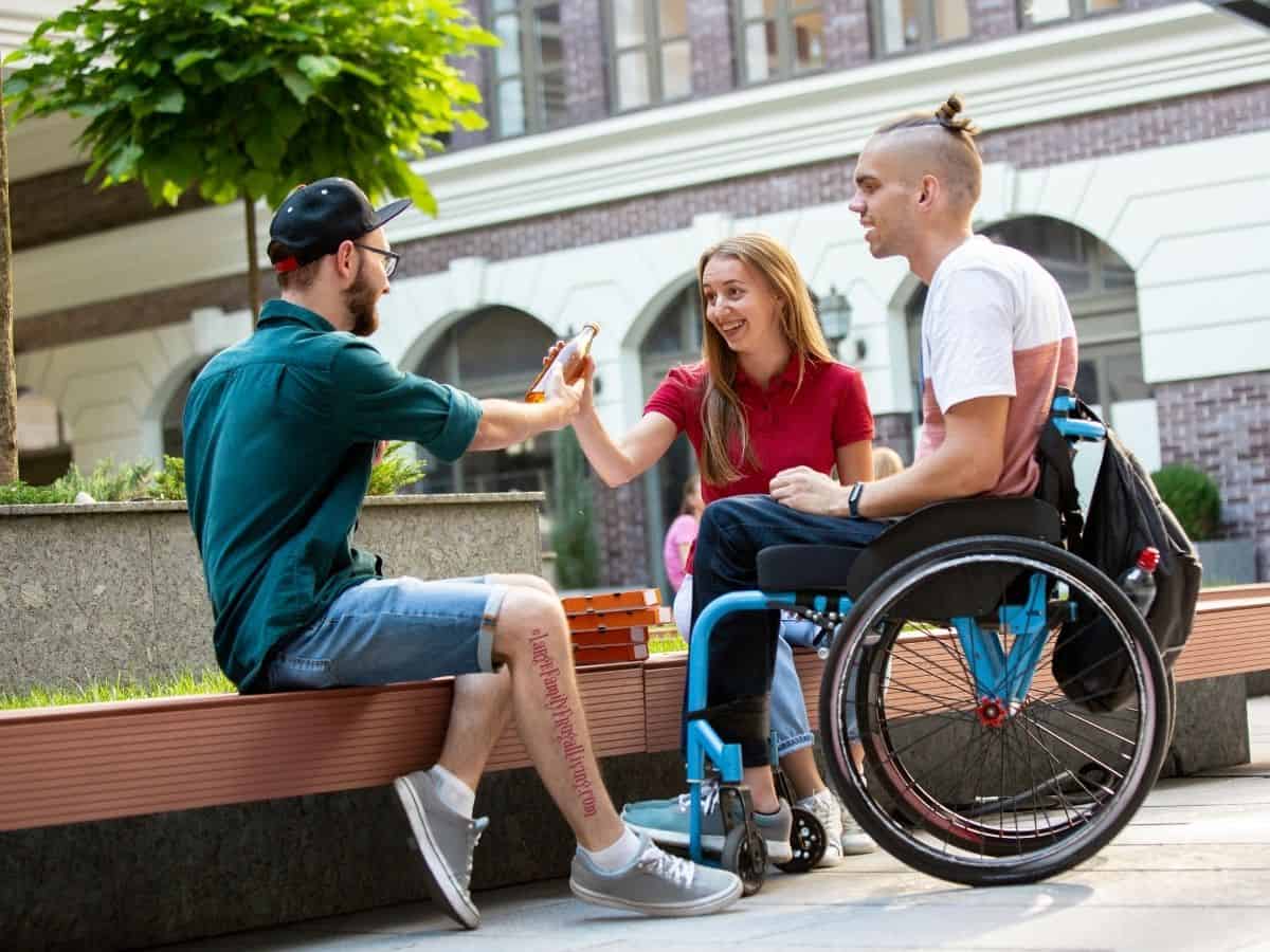 Young man in wheelchair with friends having fun in the city.