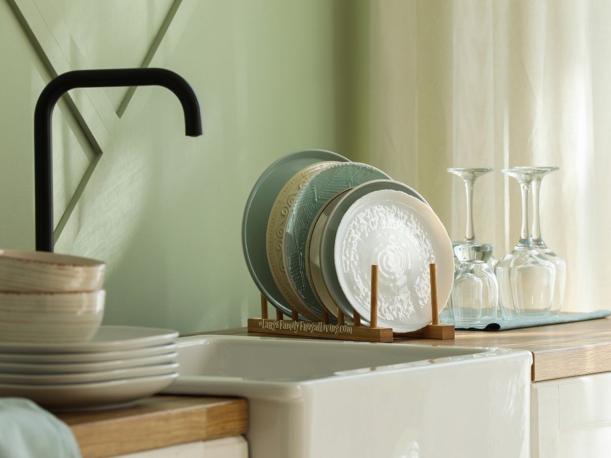 Clean dishes drying in rack beside sink. Soothing green tones and textures on plates.