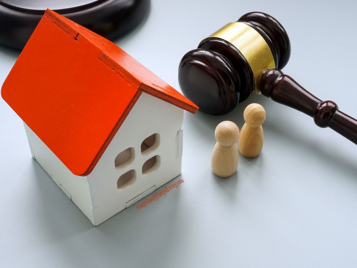Red roofed small wooden house model with two wood peg "people" and a gavel on a light colored desk