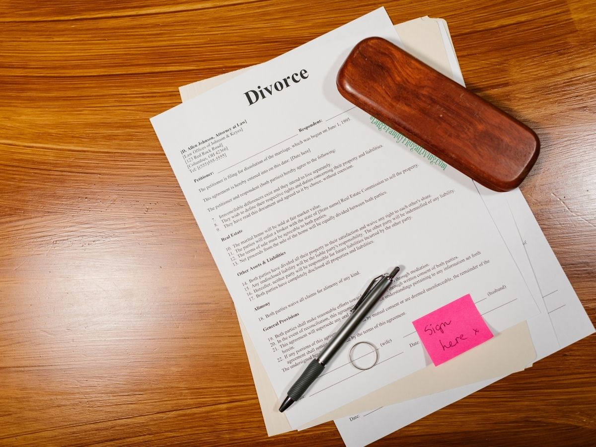 Divorce document ready to sign on wooden table with pen and ring